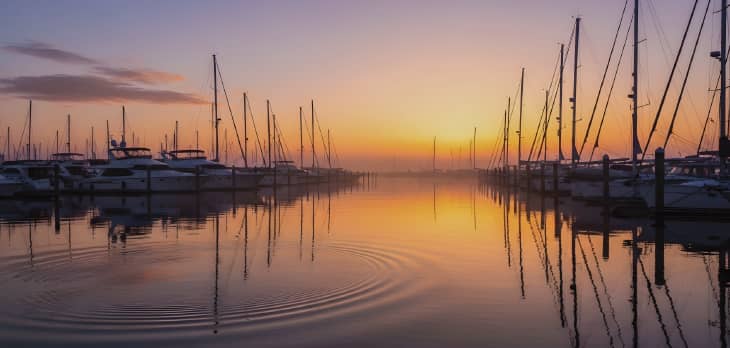sunrise on harbor with sailboats on both sides of the river